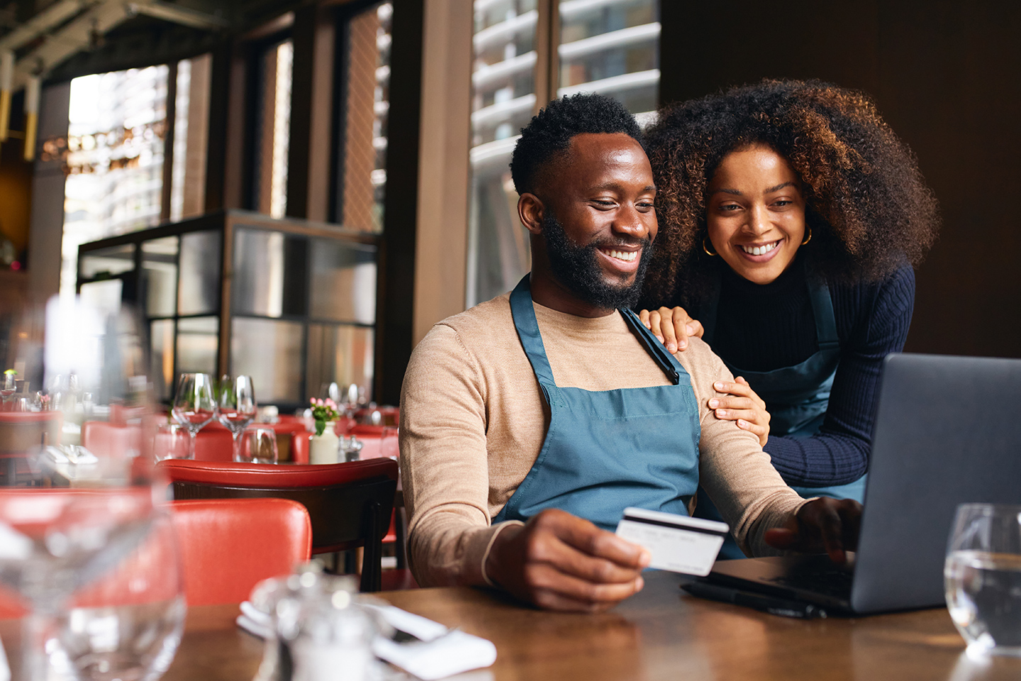 Restaurant business owners on a laptop using a credit card