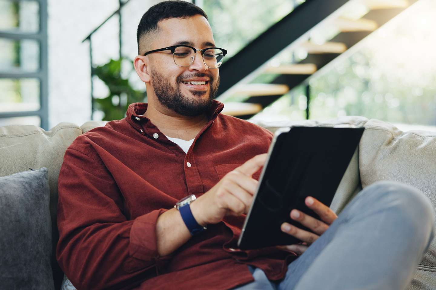 Man sitting on the couch while scrolling on his tablet