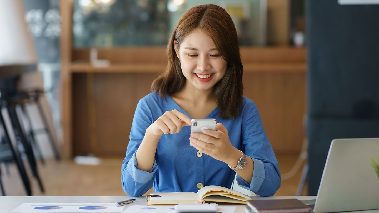 Woman banking on her phone at her desk