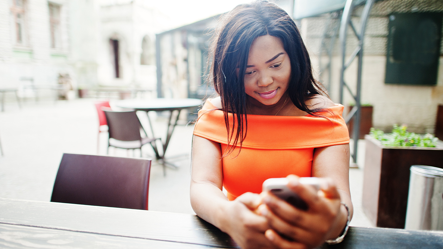 Woman in an orange shirt texting on her phone